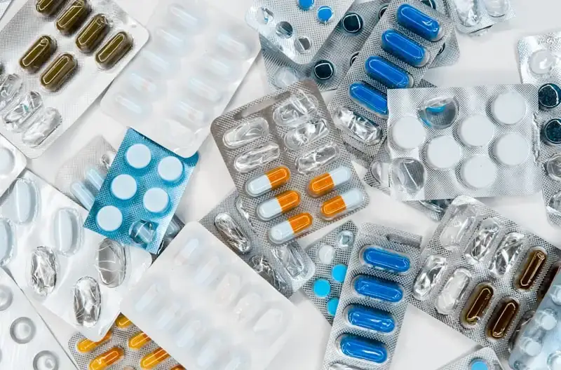 Pharmacist at counter with shelves of medicine