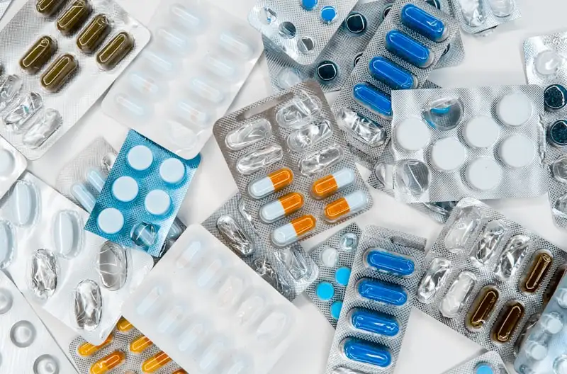Pharmacist at counter with shelves of medicine